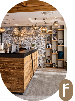 Moderne Hotelrezeption mit Holztisch, Steinwand und Hängelampen.