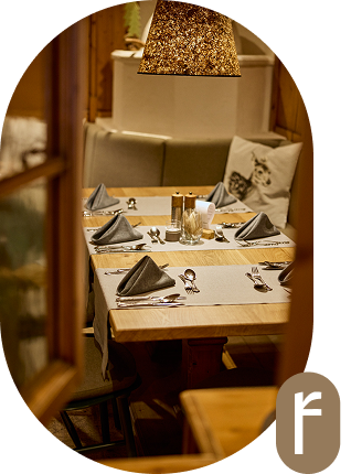 Ein gemütlich gedeckter Restauranttisch mit Servietten, Besteck und Gläsern, bereit für die Gäste.