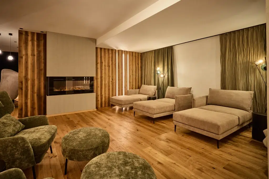 Moderne Lounge im Hotel Kaunertal mit beigen Sesseln, Holzböden und einem eingebauten Kamin.