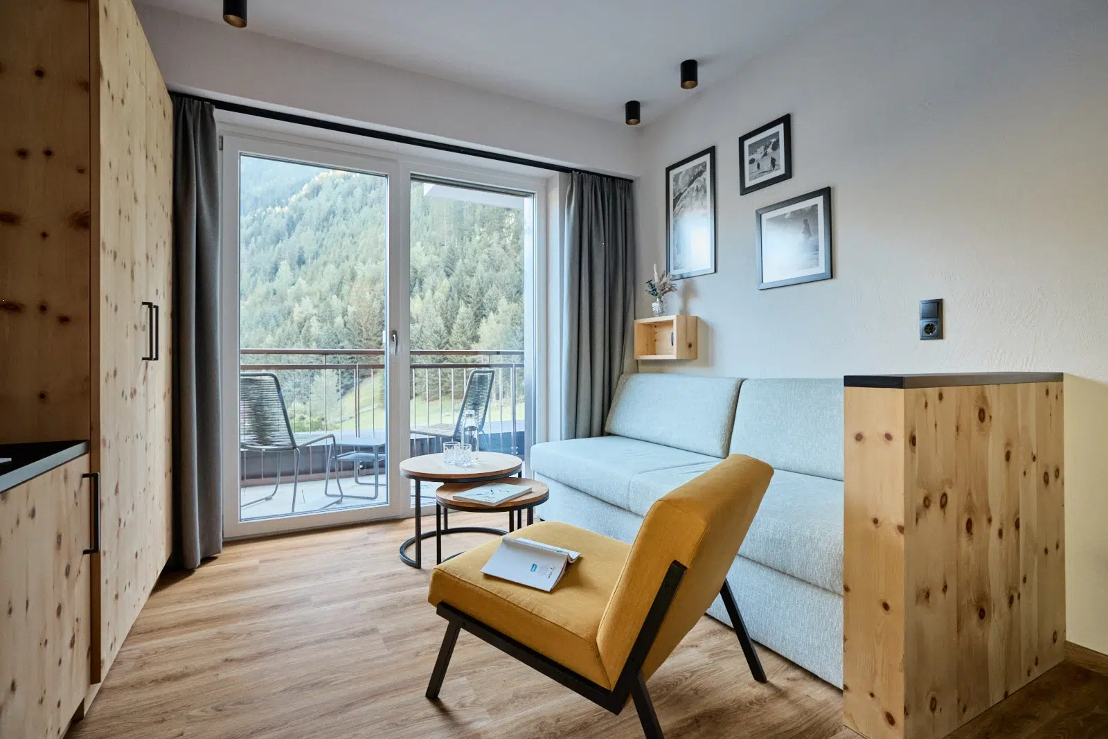 Modernes Wohnzimmer mit gelbem Sessel, hellem Sofa und Kaunertaler Familienzimmer Balkonblick.