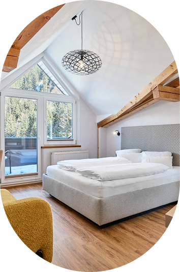 Modernes, barrierefreies Urlaubs-Dachgeschoss-Schlafzimmer mit großen Fenstern, Balken und einem Doppelbett.