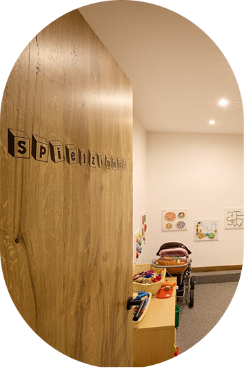 Eine Holztür mit der Aufschrift Spielzimmer öffnet sich zu einem Familienurlaub Kaunertal Kinderspielzimmer mit Spielzeug.