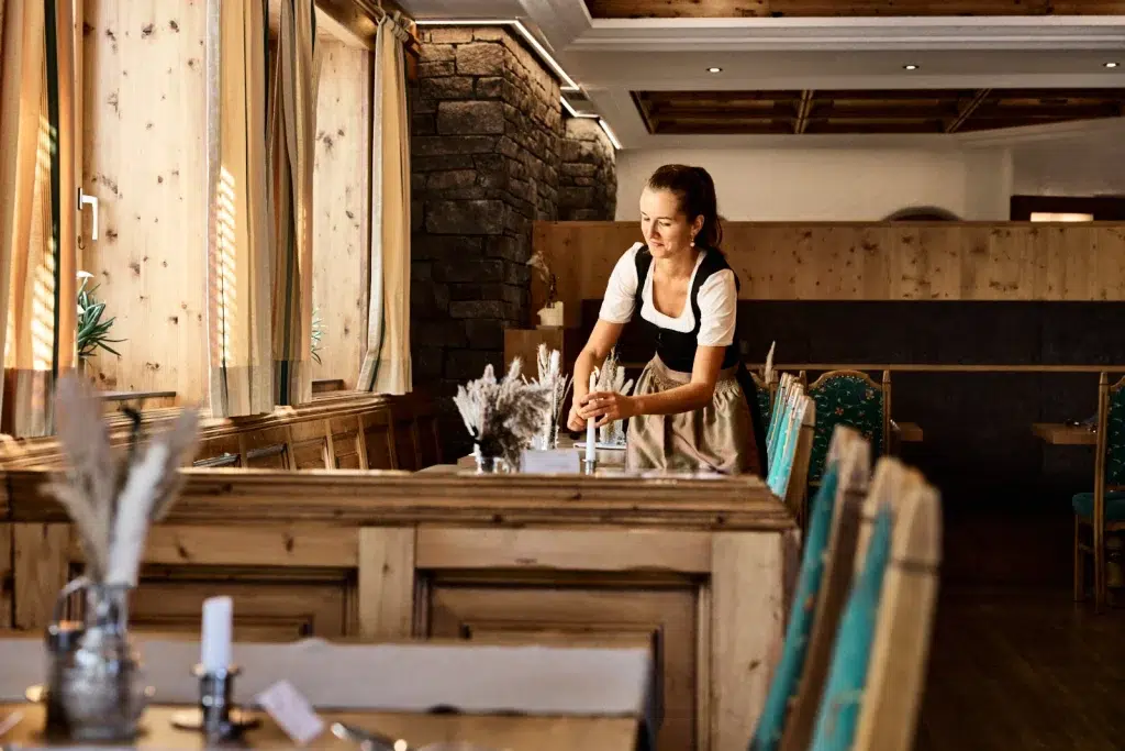 Eine Frau deckt den Tisch im gemütlichen Holzrestaurant des Hotels Kaunertal.