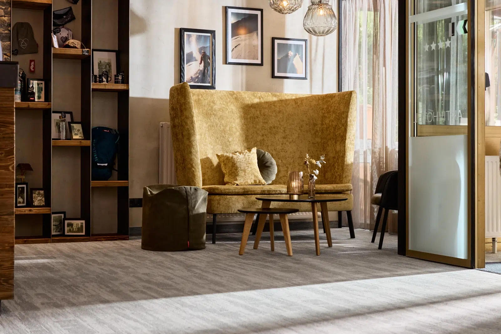 Gemütliche Lounge mit goldenem Sofa, runden Tischen, sanfter Beleuchtung und gerahmten Fotos an der Wand.
