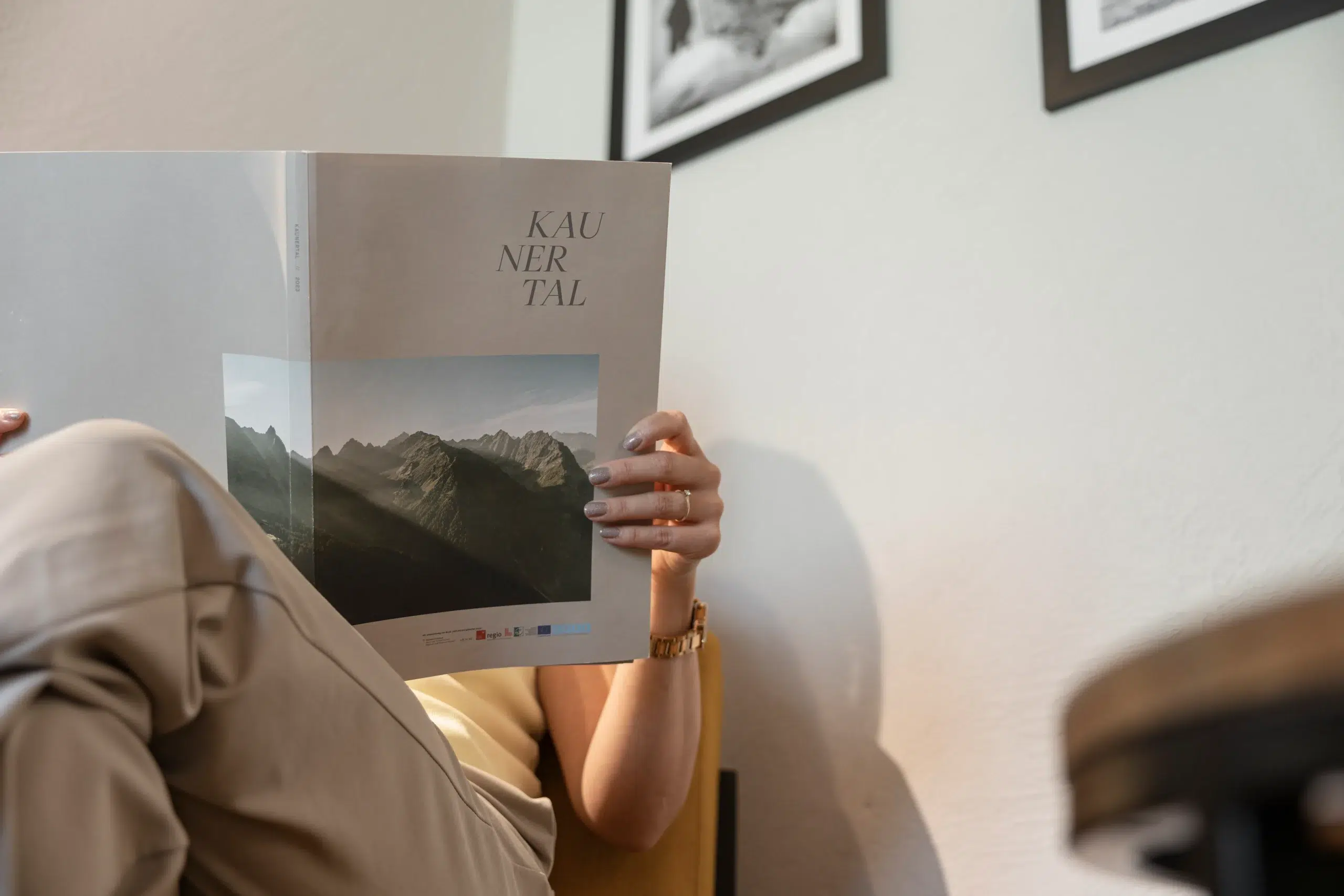 Eine Person liest eine Zeitschrift mit dem Titel KAUNERTAL, in der das Hotel Kaunertal beste Bewertungen vorstellt.