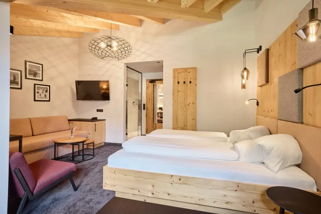 Modernes Kaunertaler Familienzimmer mit Holzakzenten, Doppelbett, Sofa, TV und gemütlicher Beleuchtung.