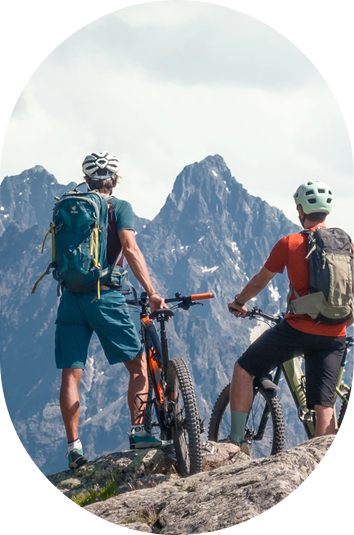 Zwei Radfahrer mit Rucksäcken bewundern die Gipfel des Kaunertaler Sommers neben ihren Rädern.