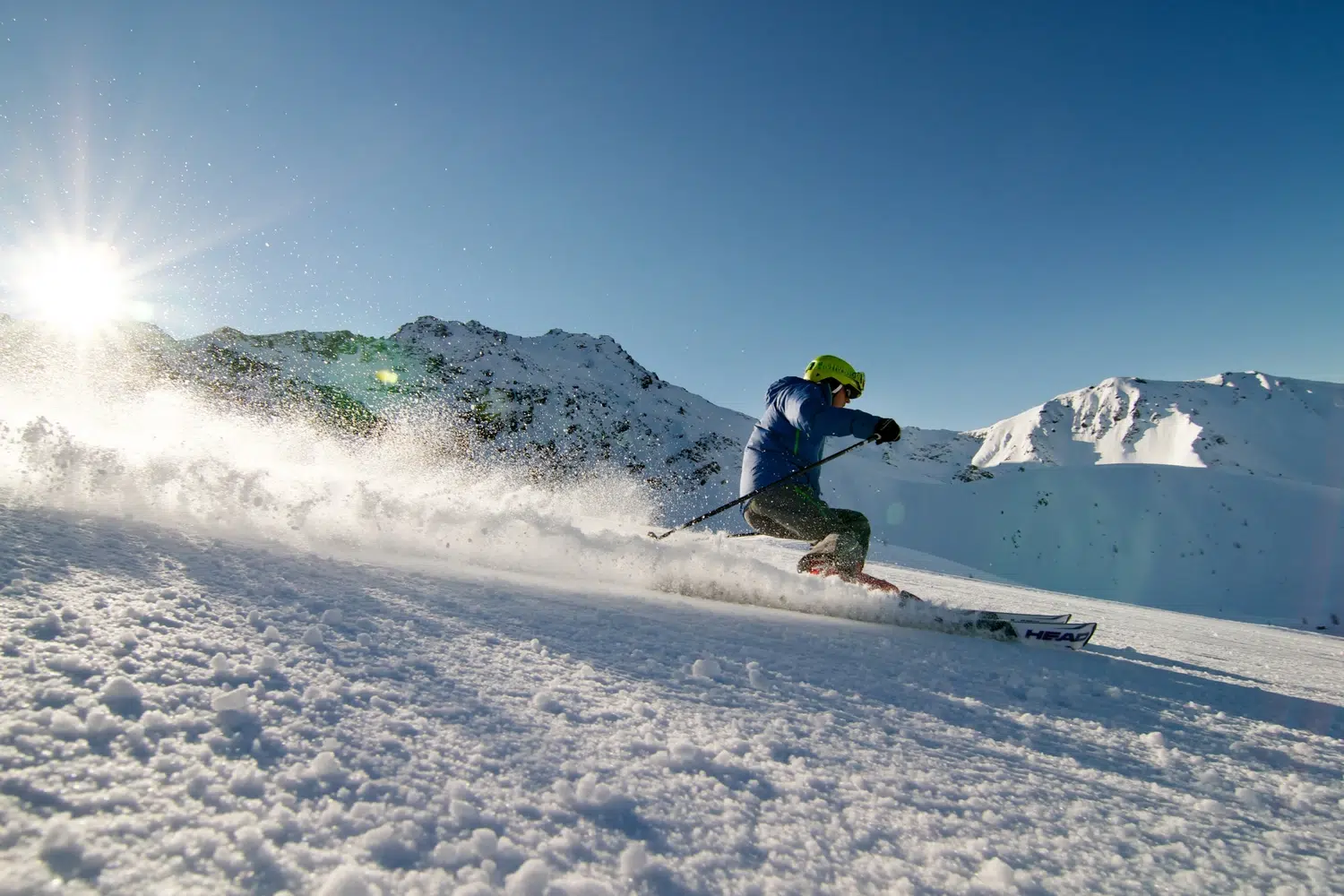 Ein Skifahrer in Bewegung auf den verschneiten Kaunertaler Winterpisten mit Sonnenschein im Hintergrund.