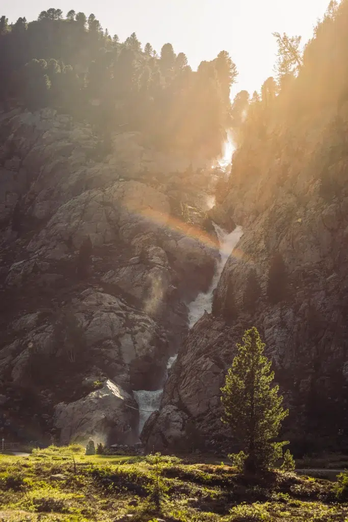 Sonnenbeschienene Wasserfallkaskaden an felsigen Klippen - perfekt für einen nachhaltigen Urlaub in der Natur.