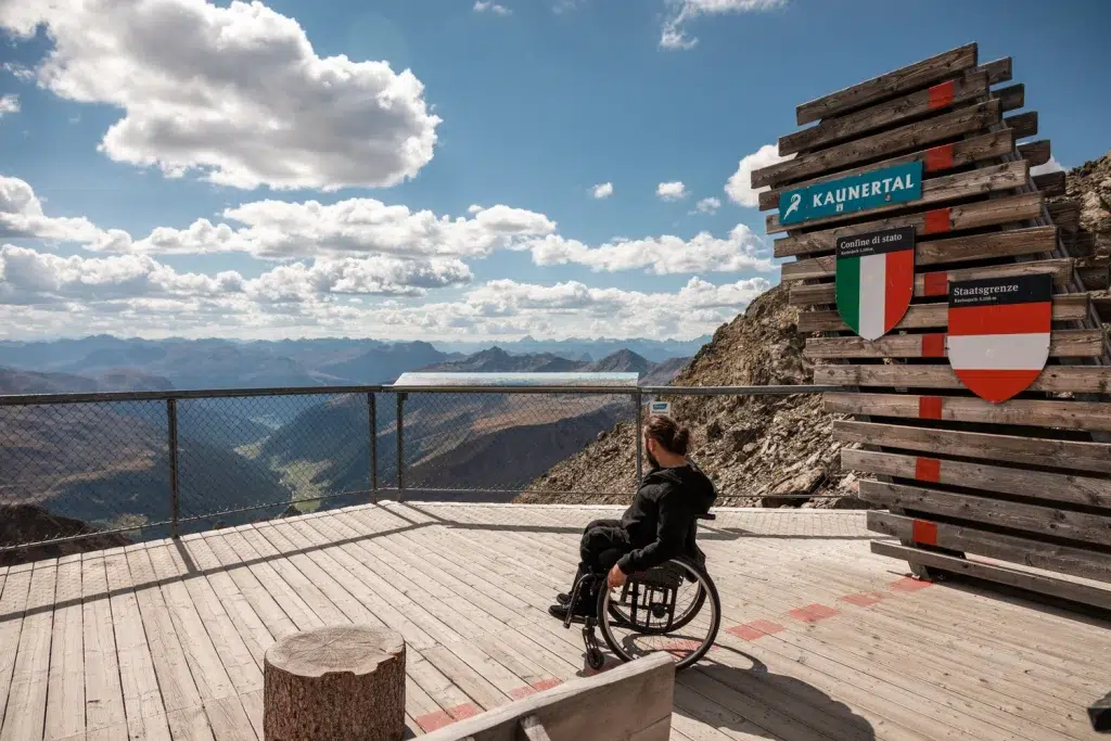 Eine Person im Rollstuhl genießt die Aussicht auf den Kaunertaler Sommer von einer barrierefreien Aussichtsplattform.